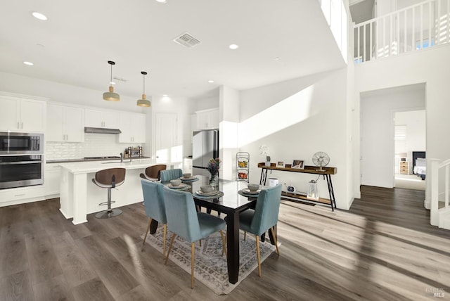 dining space featuring dark wood-type flooring and a towering ceiling