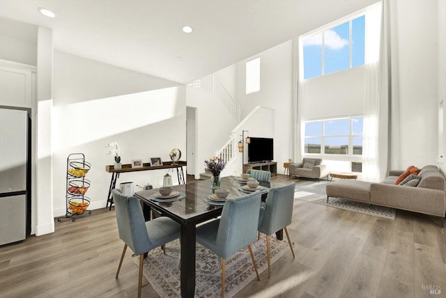 dining space featuring light hardwood / wood-style floors and a high ceiling