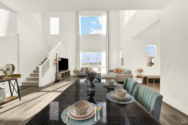 dining room featuring hardwood / wood-style floors and a towering ceiling