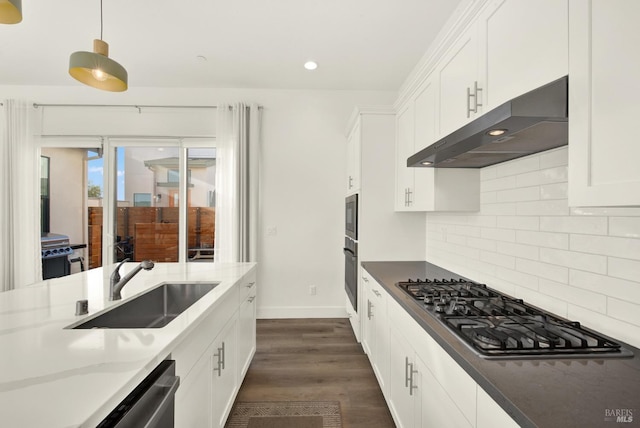 kitchen with sink, white cabinetry, decorative light fixtures, dark stone counters, and stainless steel appliances