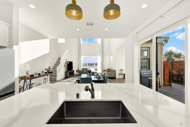 kitchen featuring sink, stainless steel fridge, light stone countertops, and white cabinets