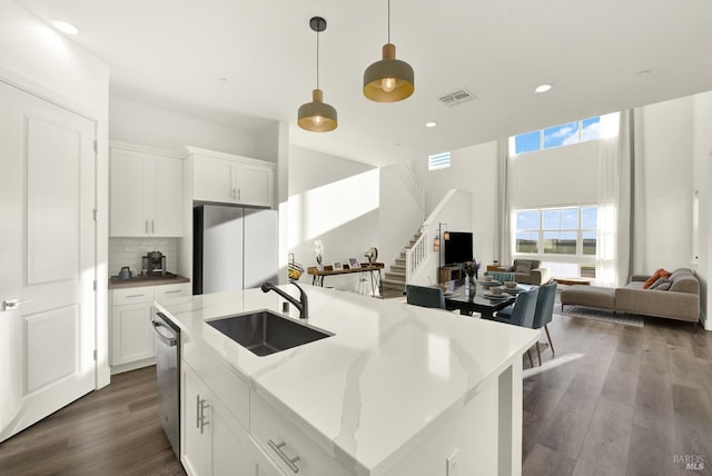 kitchen with sink, fridge, dishwasher, a kitchen island with sink, and white cabinets