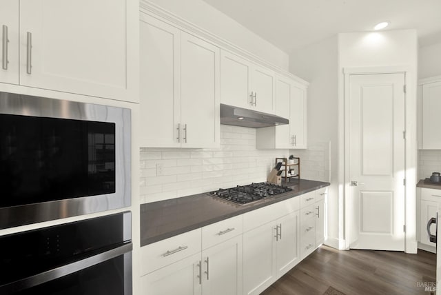 kitchen featuring white cabinetry, stainless steel appliances, dark hardwood / wood-style flooring, and decorative backsplash