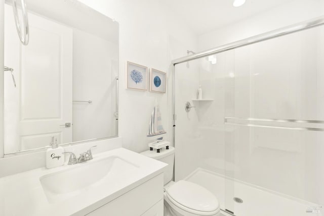 bathroom with vanity, a shower with shower door, and toilet