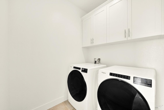 clothes washing area featuring light tile patterned floors, cabinets, and washing machine and clothes dryer