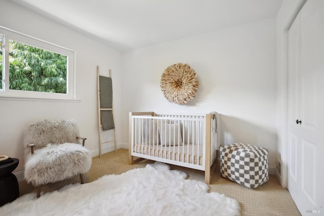 bedroom featuring a crib, carpet, and a closet