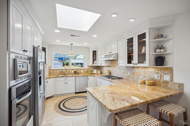 kitchen with stainless steel appliances, a kitchen breakfast bar, kitchen peninsula, and white cabinets