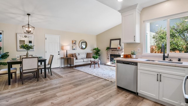 kitchen featuring sink, white cabinetry, hanging light fixtures, light hardwood / wood-style floors, and stainless steel dishwasher