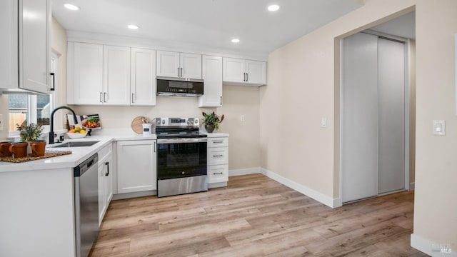 kitchen with sink, light wood-type flooring, white cabinets, and appliances with stainless steel finishes