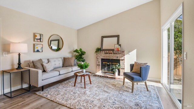 living room with a fireplace, light hardwood / wood-style floors, and vaulted ceiling