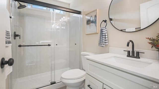 bathroom with vanity, toilet, and a shower with door