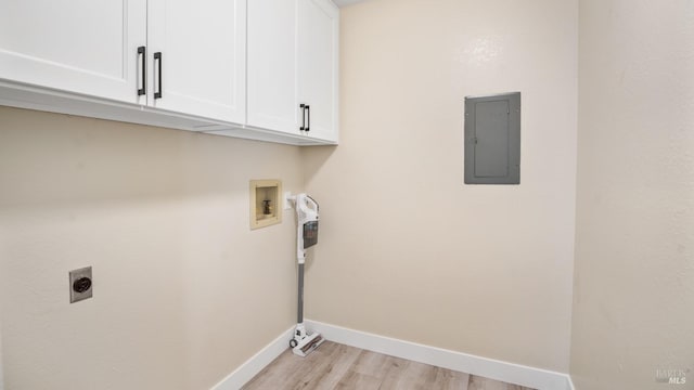 clothes washing area featuring cabinets, electric panel, hookup for a washing machine, hookup for an electric dryer, and light hardwood / wood-style flooring