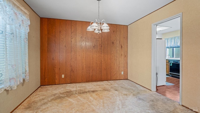 carpeted spare room featuring a notable chandelier and wooden walls