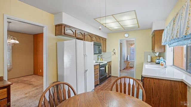 kitchen featuring decorative light fixtures, sink, light colored carpet, a notable chandelier, and black appliances