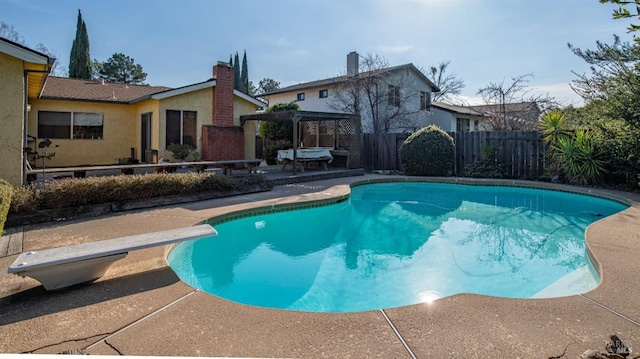 view of swimming pool with a patio, a pergola, and a diving board