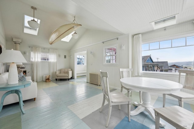 dining room featuring vaulted ceiling with skylight, plenty of natural light, radiator heating unit, and light wood-type flooring