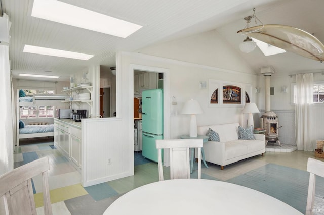 living room featuring lofted ceiling with skylight and a wood stove