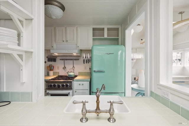 kitchen with fridge, sink, tile countertops, and high end stainless steel range