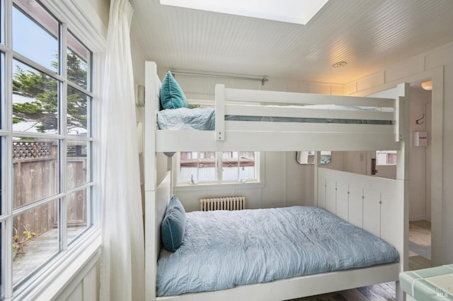 bedroom with multiple windows, radiator, and a skylight