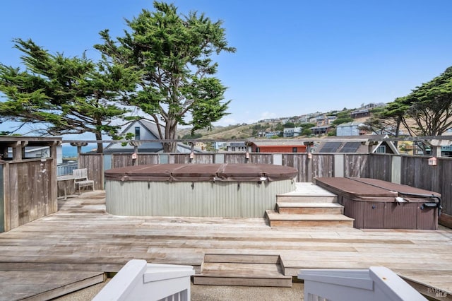 wooden terrace with a hot tub and a water view