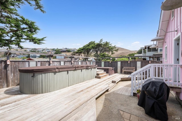 wooden terrace featuring a grill, a mountain view, and a hot tub