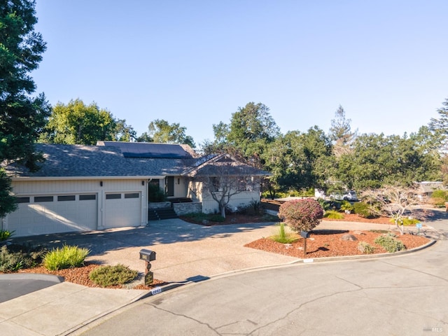 ranch-style home with a garage, driveway, and roof with shingles