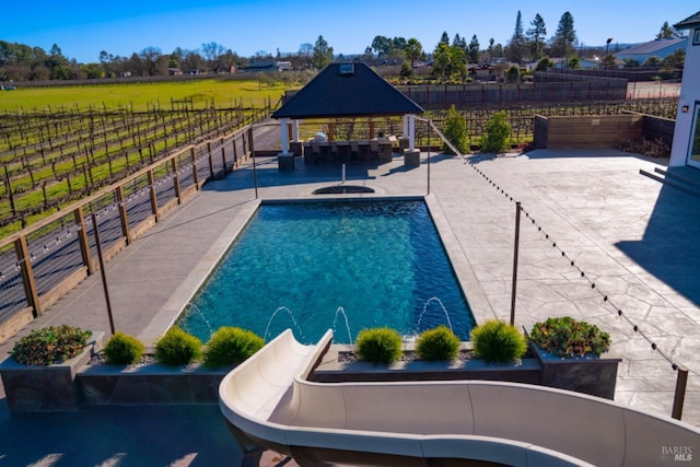 view of swimming pool featuring a gazebo, pool water feature, a water slide, and a patio area