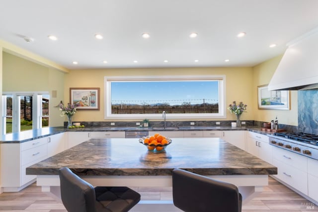 kitchen with sink, a breakfast bar, white cabinetry, stainless steel appliances, and a kitchen island