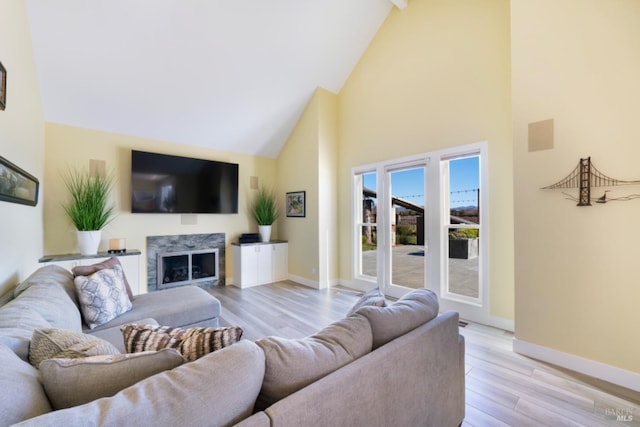 living room featuring a premium fireplace, high vaulted ceiling, and light hardwood / wood-style flooring