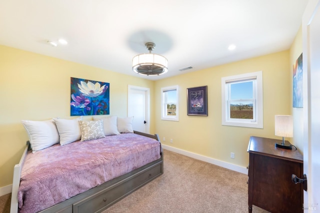 bedroom featuring light colored carpet and multiple windows