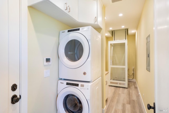 laundry room featuring stacked washer / drying machine and light hardwood / wood-style flooring