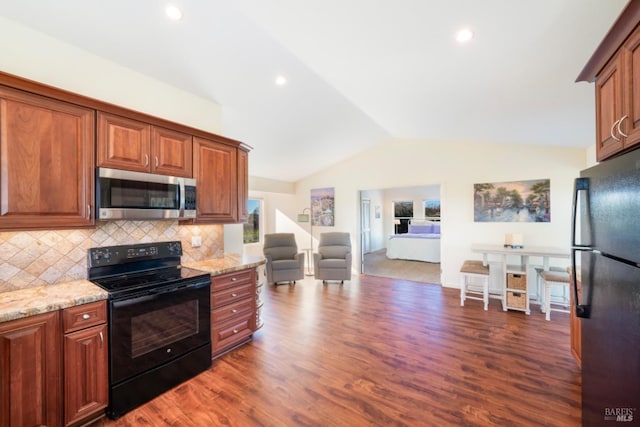 kitchen with dark wood-type flooring, light stone counters, black appliances, vaulted ceiling, and backsplash