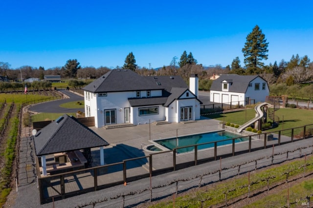 rear view of house featuring a pool with hot tub and a patio