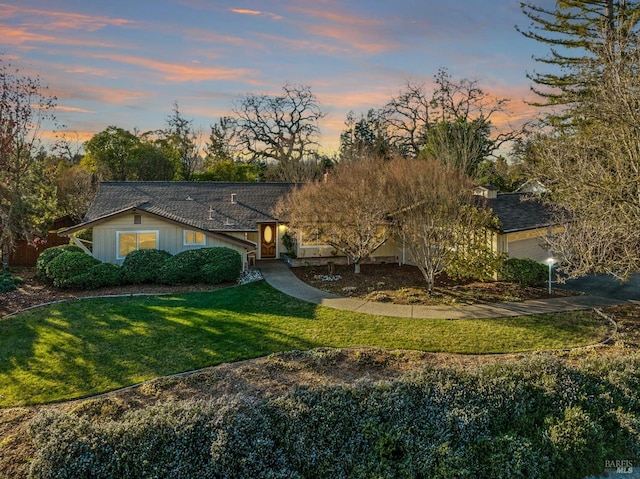 ranch-style home featuring driveway, an attached garage, and a lawn