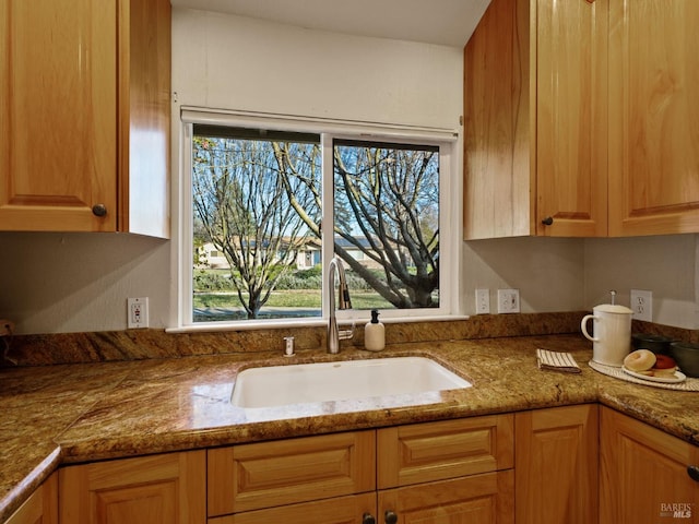 kitchen featuring stone counters and a sink