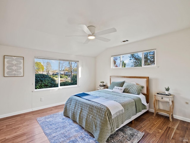 bedroom featuring visible vents, baseboards, wood finished floors, a ceiling fan, and lofted ceiling