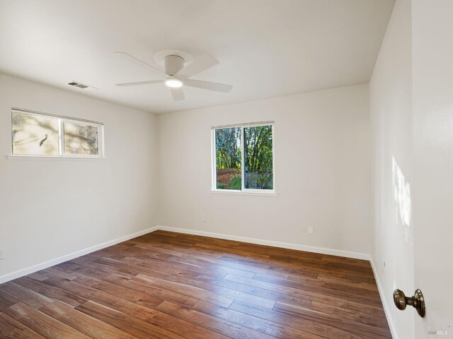 empty room with a ceiling fan, baseboards, visible vents, and wood finished floors