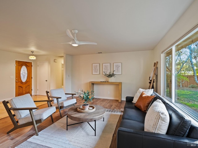 living room featuring wood finished floors, a ceiling fan, and baseboards