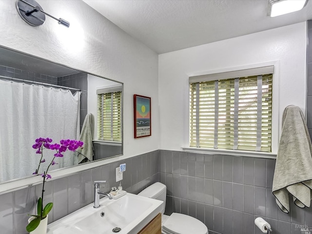 bathroom with walk in shower, sink, tile walls, and toilet