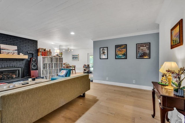 living room with crown molding, a fireplace, and light wood-type flooring