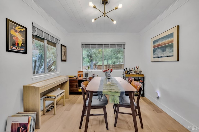 dining area with crown molding, an inviting chandelier, and light wood-type flooring