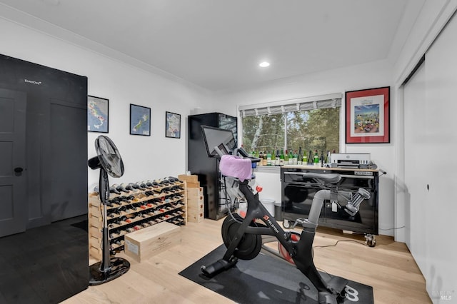 workout area featuring ornamental molding and light hardwood / wood-style flooring