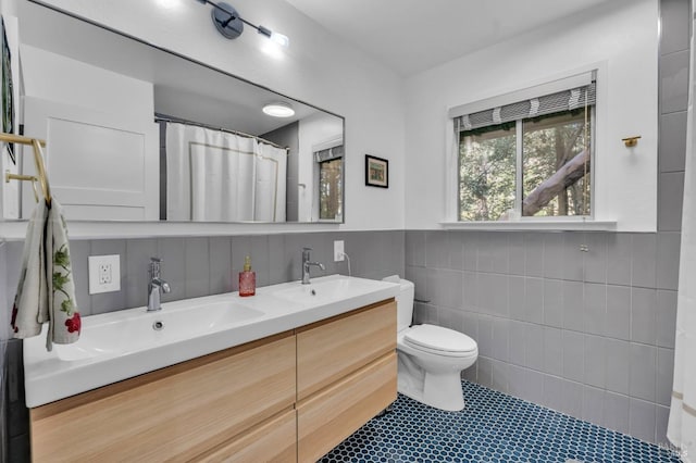 bathroom with vanity, toilet, and tile walls