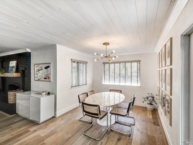 dining space featuring wood ceiling, crown molding, a brick fireplace, an inviting chandelier, and light hardwood / wood-style flooring