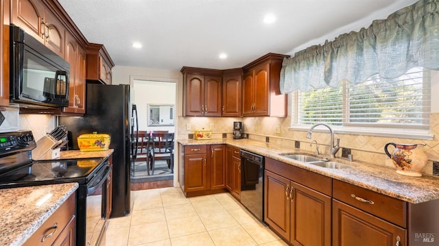 kitchen featuring sink, backsplash, light tile patterned floors, black appliances, and light stone countertops