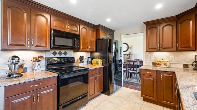 kitchen with backsplash, light stone countertops, light tile patterned floors, and black appliances