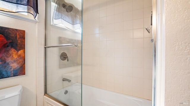 bathroom with toilet and combined bath / shower with glass door