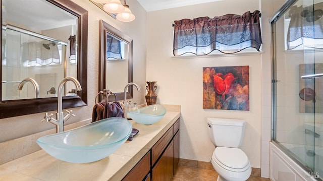 full bathroom featuring vanity, tile patterned flooring, bath / shower combo with glass door, and toilet