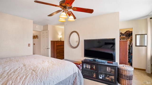 bedroom featuring light carpet, a spacious closet, a closet, and ceiling fan