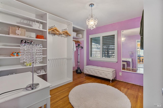 walk in closet with hardwood / wood-style floors and a chandelier